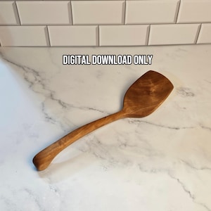 May include: A wooden spatula with a smooth, curved handle and a wide, flat head featuring natural wood grain patterns. The text DIGITAL DOWNLOAD ONLY is printed in black above the spatula, which is positioned on a white marble surface.