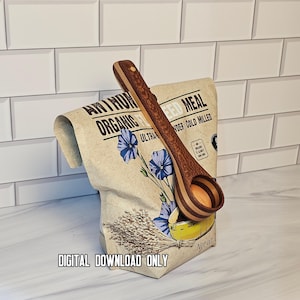 May include: A wooden scoop with a layered, striped handle rests against a paper bag of organic flaxseed meal. The bag features illustrations of blue flax flowers and a bundle of seeds. The text DIGITAL DOWNLOAD ONLY is printed at the bottom.