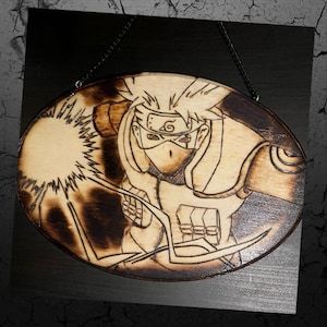 Puede incluir: Placa ovalada de madera con una obra de arte pirograbada de un personaje de anime. La obra representa a un personaje con pelo puntiagudo, una máscara y una diadema. El fondo es oscuro y la placa está suspendida por una cadena negra.