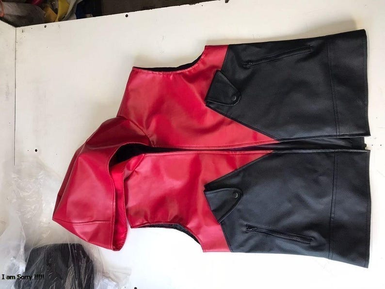 May include: A two-tone vest in red and black. The vest features a red front and hood, with black panels on the sides and back. It has a zipper closure and small pockets. The garment is made of a smooth, possibly leather-like material.