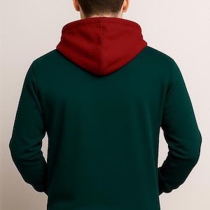 May include: A dark green hoodie with a burgundy hood and hem. The back view of the hoodie shows a contrasting color scheme, with the hood and hem in a deep burgundy shade. The hoodie is made of a soft material.
