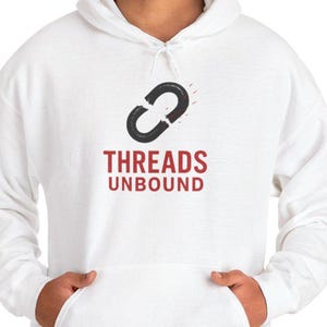 Puede incluir: Sudadera con capucha blanca con bolsillo delantero y el texto "THREADS UNBOUND" en rojo y negro. El diseño presenta un gráfico de eslabón de cadena negro encima del texto. La sudadera es de estilo casual.