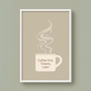 May include: A framed print featuring a coffee cup with steam rising above it. The cup has the text "Coffee first, Tickets, Later" in a simple, modern font. The background is a neutral beige color.