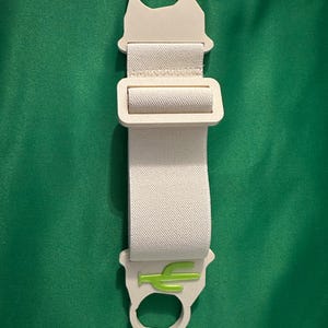 Pode incluir: Uma correia creme com um log&oacute;tipo de cacto verde. A correia tem uma fivela e duas argolas. O fundo &eacute; de cor verde lisa.