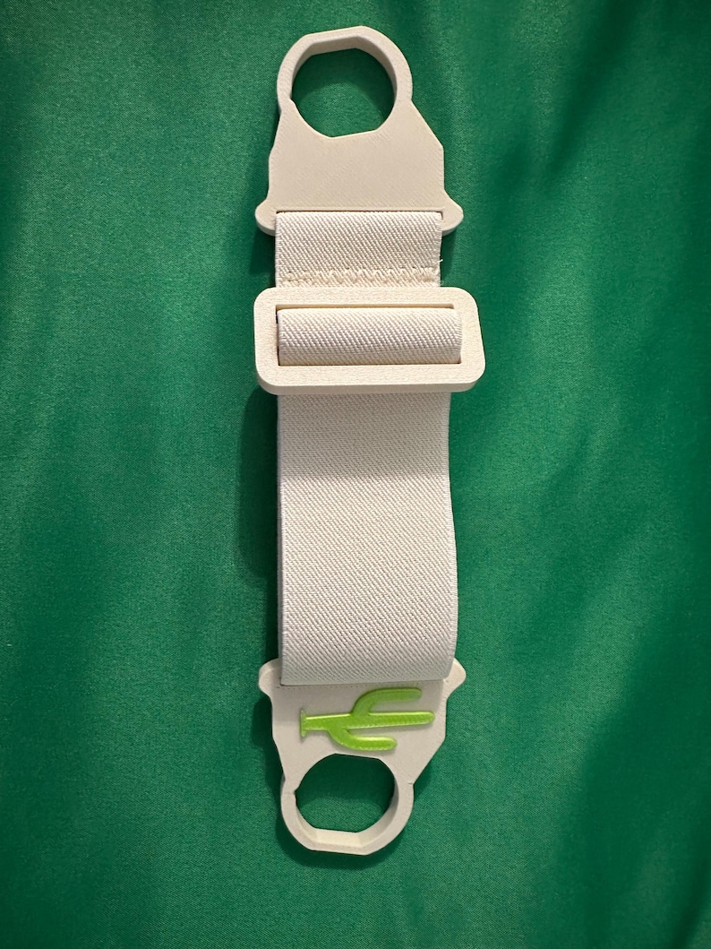 Pode incluir: Uma correia creme com um log&oacute;tipo de cacto verde. A correia tem uma fivela e duas argolas. O fundo &eacute; de cor verde lisa.
