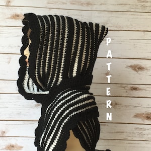 Op de afbeelding: Zwart-wit gestreepte gehaakte kapuchon sjaal met een gegolfde rand. De sjaal wordt getoond op een mannequin.