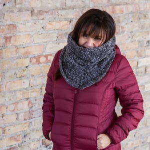 Peut inclure: Une femme portant une veste matelassée bordeaux avec une écharpe en tricot gris à col montant.