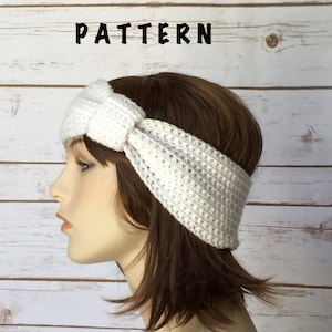 May include: White crocheted headband with a knotted detail. The headband is worn on a mannequin with brown hair.