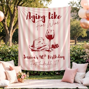 May include: A rectangular fabric backdrop featuring vertical light pink and white stripes. The text reads Aging like Fine Wine, Jessica's 40th Birthday, and Fort Lauderdale, Fl. A dark red illustration shows a slice of cheese and a wine glass.