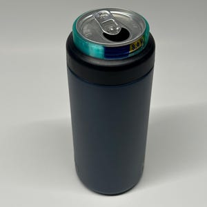 May include: A navy blue can cooler with a black rim and a silver can with an open tab. The can has a teal and blue band around the top. The can is 8.4 fl oz.