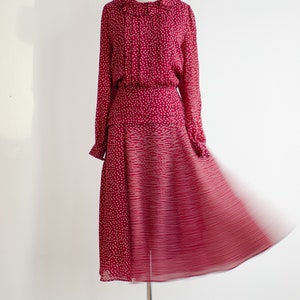 May include: A red dress with a white polka dot pattern and a ruffled collar. The skirt is a-line and has a gradient pattern.