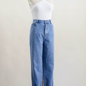 May include: A white halter top and light blue denim jeans displayed on a mannequin. The jeans have a high waist and are cuffed at the ankles. The top has a criss-cross design.