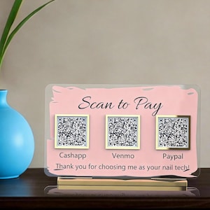 May include: A pink and gold acrylic sign with the words "Scan to Pay" and QR codes for Cashapp, Venmo, and Paypal. The sign also includes the text "Thank you for choosing me as your nail tech!"