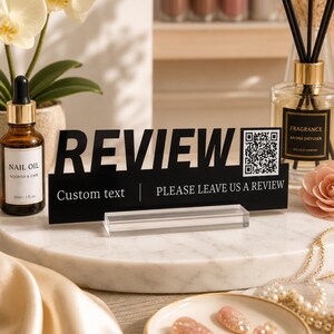 Könnte beinhalten: Ein schwarzes rechteckiges Schild mit einem klaren Acrylsockel, das das Wort REVIEW in großen fetten Buchstaben, einen QR-Code und den Text Custom text | PLEASE LEAVE US A REVIEW zeigt. Das Schild besteht aus flachem Material mit weißem Aufdruck.