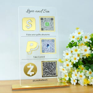 Op de afbeelding: Een helder acryl bord met gouden accenten toont de tekst "Love and Sin" en betalingssymbolen voor Cash App, PayPal en Zelle, samen met bijbehorende QR-codes. Het bord bevat ook de tekst "Enjoy your guilty pleasures" en "Take Control."