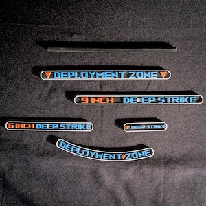 May include: A collection of black and blue decals with white text. The decals include the phrases "DEPLOYMENT ZONE" and "6 INCH DEEP STRIKE". Other decals read "9 INCH DEEP STRIKE" and "3 DEEP STRIKE".