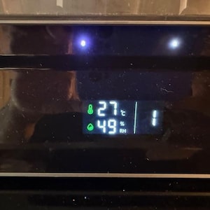 Puede incluir: Una pantalla digital que muestra la temperatura a 27 grados Celsius y la humedad al 49%. La pantalla tambi&eacute;n muestra el n&uacute;mero 1. La pantalla es verde sobre un fondo negro.