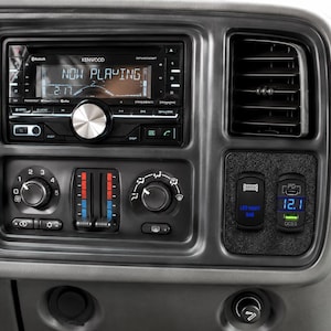 May include: A car dashboard with a Kenwood stereo displaying "NOW PLAYING" and a digital clock. Below are climate controls and a panel with LED light bar and power delivery switches, and a digital display showing "12.1".