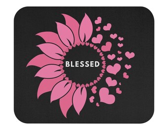 Peut inclure: Tapis de souris noir avec un motif de tournesol rose et le mot "BLESSED" au centre. Des cœurs roses sont dispersés autour du tournesol. Le tapis de souris a une forme rectangulaire arrondie.