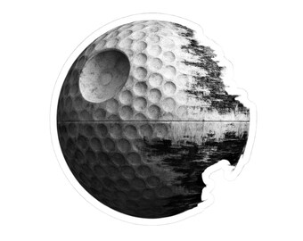May include: Black and white sticker featuring a golf ball design reimagined as the Death Star from Star Wars. The sticker has a distressed, textured appearance, with a large circular indentation and a rough, dark side.