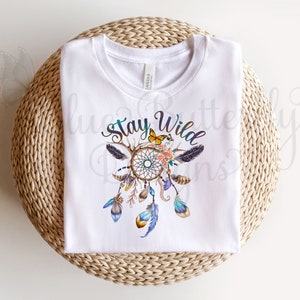 May include: White t-shirt with a colorful dreamcatcher design and the text "Stay Wild".