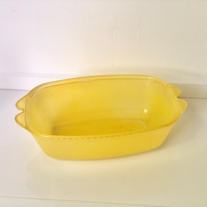 Op de afbeelding: Een doorschijnende gele rechthoekige ovenschaal met afgeronde hoeken en twee handvatten aan weerszijden. De schaal is gemaakt van een helder, duurzaam materiaal en is leeg. De schaal staat op een wit oppervlak.