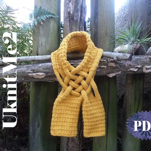 May include: A yellow knitted scarf with a braided design. The scarf is hanging on a wooden fence. The text "KnitMe2" is visible on the left side of the image. The text "PDF" is visible in the lower right corner of the image.