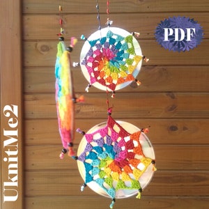 May include: Three colorful crocheted rainbow mandala wall hangings with black beads and tassels hanging from a wooden surface. The text "PDF" is visible in the upper right corner of the image.