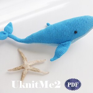 May include: A light blue crocheted whale toy with a small black eye. A beige starfish lies beside the whale. The text "UknitMe2 PDF" is visible in the bottom right corner of the image.
