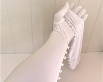 May include: White long gloves with pearl embellishments along the side. The gloves are made of a soft, stretchy fabric.
