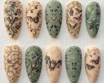 May include: A set of ten almond-shaped press-on nails featuring intricate illustrations of bats, dark berries, and swirling botanical vines. The color palette includes shades of cream, beige, sage green, and deep purple, with detailed line work.