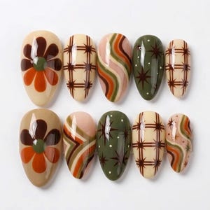 May include: A set of ten almond-shaped press-on nails featuring a variety of designs including brown and orange flowers, brown plaid patterns, wavy lines in shades of green and orange, and dark green backgrounds with brown starbursts and white dots.