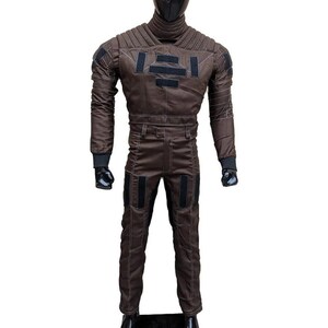 May include: Brown jumpsuit with black accents, featuring a high collar and quilted shoulder design. The suit includes a matching pair of pants and a black face covering. The overall design suggests a futuristic or tactical theme.