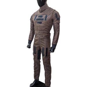 May include: Brown jumpsuit with black accents, displayed on a mannequin. The suit features a high collar, multiple patches, and a belt. Black gloves and boots complete the outfit. The jumpsuit has a futuristic design with geometric patterns.