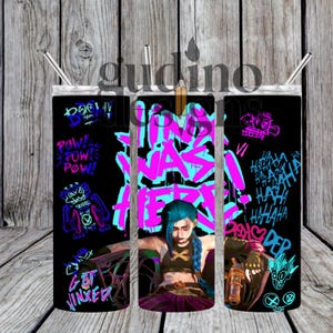 May include: A black tumbler with a design featuring a character with blue hair and the text "WAS HERE" in pink and blue. The tumbler also has other graphics and text, including "POW!" and "GET JINXED". Includes a silver straw.