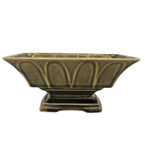May include: A rectangular, olive-green ceramic bowl with a pedestal base. The bowl has a series of arched cutouts along the top edge. The base is square and stepped. A decorative piece for the home.