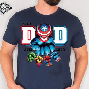 A man wearing a blue t-shirt with a graphic design featuring a superhero character and the text "Best Dad Ever".