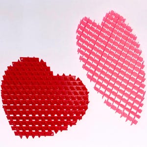 May include: Two heart-shaped objects with a lattice design. One is red, the other is pink. The objects are made of a series of small, connected, rectangular shapes, creating a three-dimensional effect. The background is white.