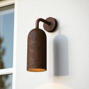 Pu&ograve; includere: Applique da parete per esterni color bronzo con paralume cilindrico e braccio curvo. L'applique &egrave; montata su una piastra posteriore circolare. L'apparecchio ha una finitura strutturata e proietta un bagliore caldo.