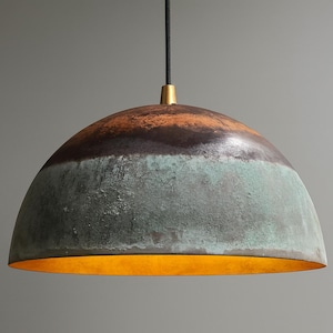 May include: A dome-shaped pendant light fixture with a textured, multi-toned surface. The top section is brown, transitioning to a dark band, then a turquoise-green lower section. The interior glows with a warm, golden light.