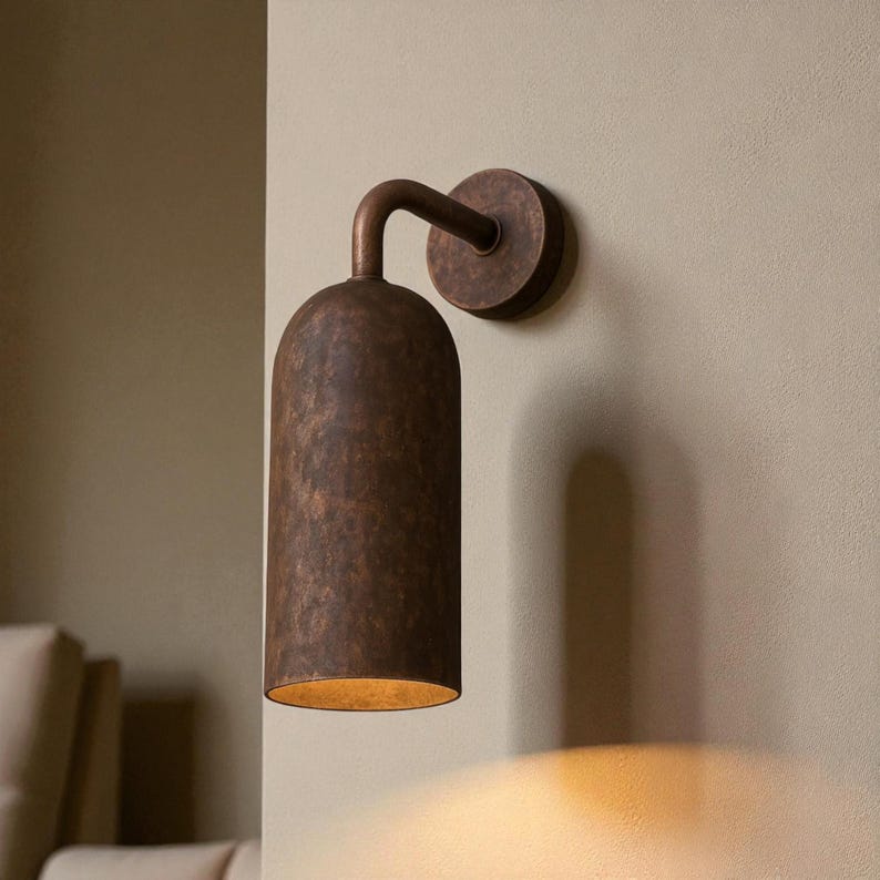 Pu&ograve; includere: Applique da parete color bronzo con paralume cilindrico e braccio curvo. L'applique &egrave; montata su una base circolare e proietta una luce calda. L'apparecchio ha una superficie strutturata e un'estetica vintage.