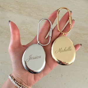 Può includere: Due portachiavi in metallo di forma ovale con moschettoni. Un portachiavi è color argento e inciso con il nome Jessica in corsivo. L'altro portachiavi è color oro e inciso con il nome Michelle in corsivo.
