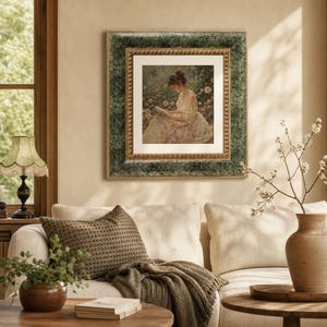 May include: A square framed wall art piece featuring a painting of a person in a light-colored dress reading a book amidst flowers. The frame has a textured, mottled green outer border and a decorative gold inner border with a beaded edge detail.