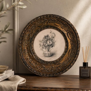 May include: A circular wall art piece featuring a black and white botanical sketch of flowers in a pitcher, encased in a wide, ornate, distressed gold-toned frame with intricate leaf and floral relief carvings along the outer border.