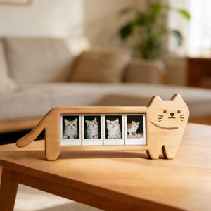May include: A wooden cat-shaped photo frame holding four small photos of cats. The frame is light brown and has a simple, cartoon-like design. The photos feature different cats with various markings, adding a touch of whimsy to the decor.