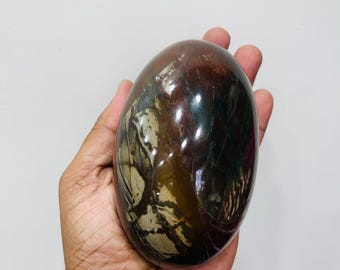 May include: A polished, oval-shaped stone featuring a deep mahogany and dark brown base color with intricate, contrasting cream and tan veining patterns that create a marbled appearance across the smooth, reflective surface of the mineral specimen.