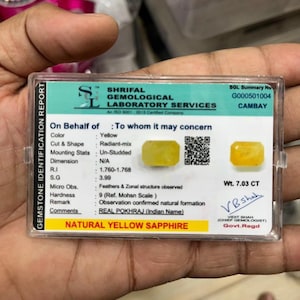 May include: A rectangular Shrifal Gemological Laboratory Services identification report for a 7.03 CT natural yellow sapphire. The card features a radiant-mix cut yellow gemstone, a QR code, and technical data including R.I 1.760-1.768 and S.G 3.99.