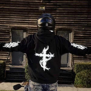 Reflective black hoodie featuring bright white cross and sleeve graphics for high visibility during night rides and stylish streetwear look.