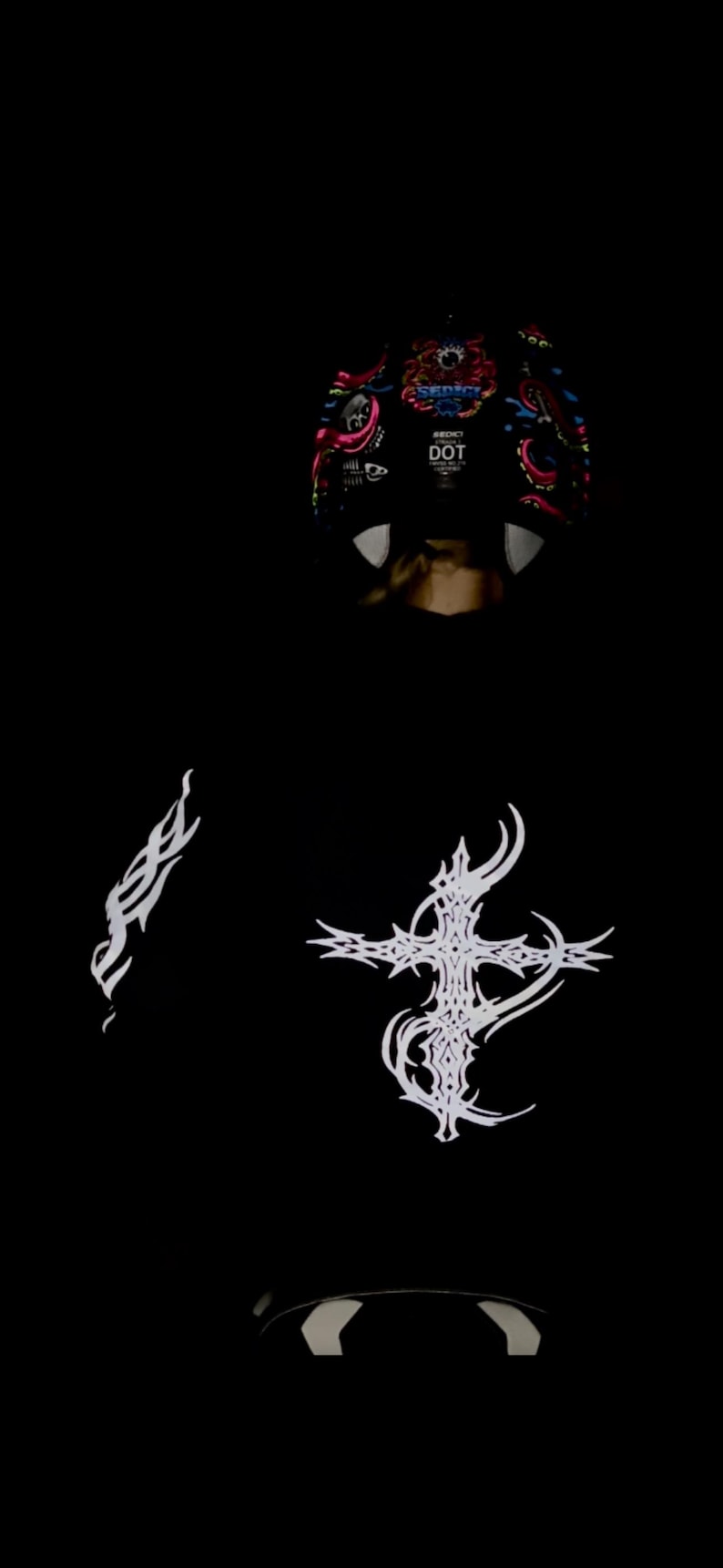 Pu&ograve; includere: Felpa con cappuccio nera con disegni a croce e fiamma tribali bianchi. La parte superiore della felpa con cappuccio presenta un design grafico colorato con la scritta "SEDICT" e la scritta "DOT".