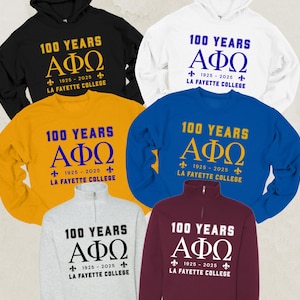 May include: Assortment of sweatshirts and hoodies in various colors, including black, white, gold, blue, and burgundy. Each garment features the text "100 YEARS" above the Greek letters ΑΦΩ, with "1925-2025" and "LA FAYETTE COLLEGE" below.